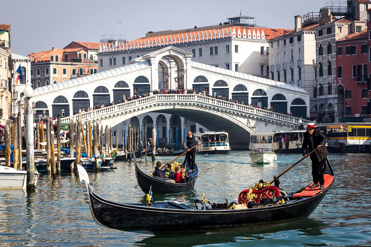 Teens watch gondolas glide along a Venice canal near the Rialto Bridge