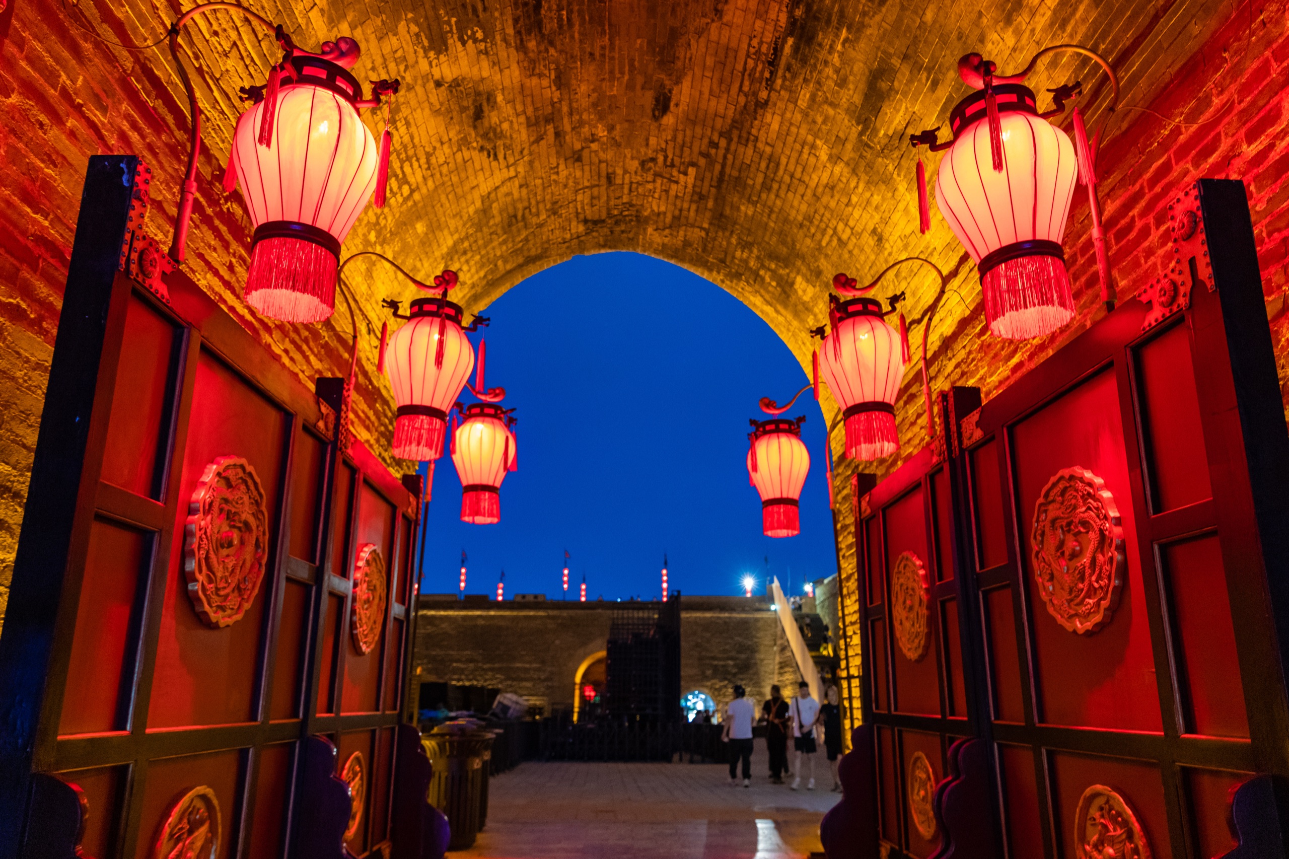 Red lanterns lighting a brick gate arch in the Xi'an City Wall, China, at dusk
