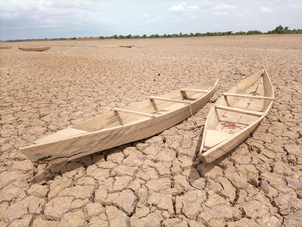 wooden boats rest on the dry, cracked earth in Burkina Faso. Learn fun facts about Burkina Faso.